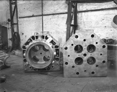 821693 Afbeelding van enkele gietstukken (onderdelen voor scheepsmotoren) bij de N.V. Nederlandse Staalfabrieken DEMKA ...